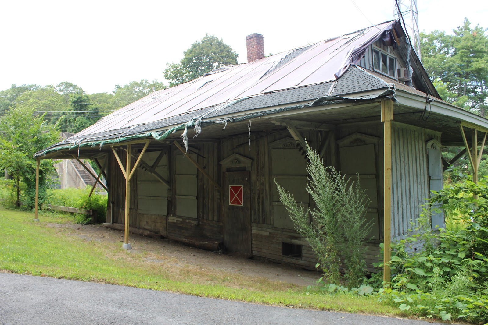 A historic train station in rough condition sitting on the Massachusetts Centrail Rail Trail.